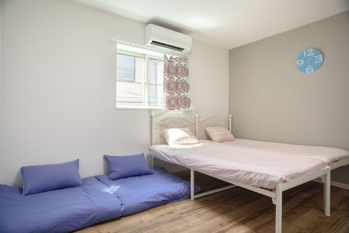 Eine kleine Einzimmerwohnung mit Bett, Sofa und Wanduhr.