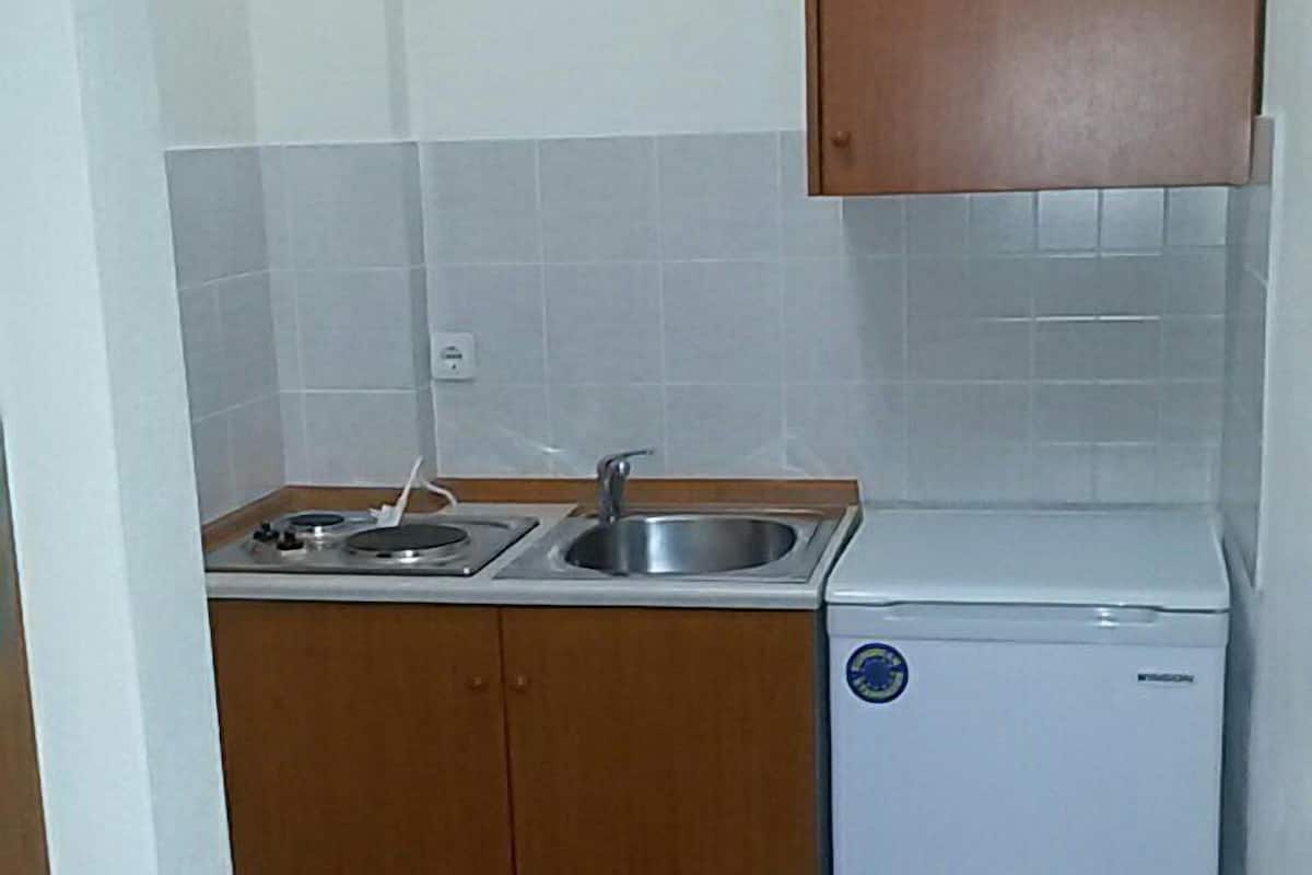 Eine kleine Küche mit Holzausstattung, einem Spülbecken und einem kleinen, weißen Kühlschrank.