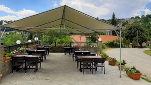 An outdoor patio with tables and chairs, surrounded by potted plants and a canopy. - Guest House Ilektra (Voio)