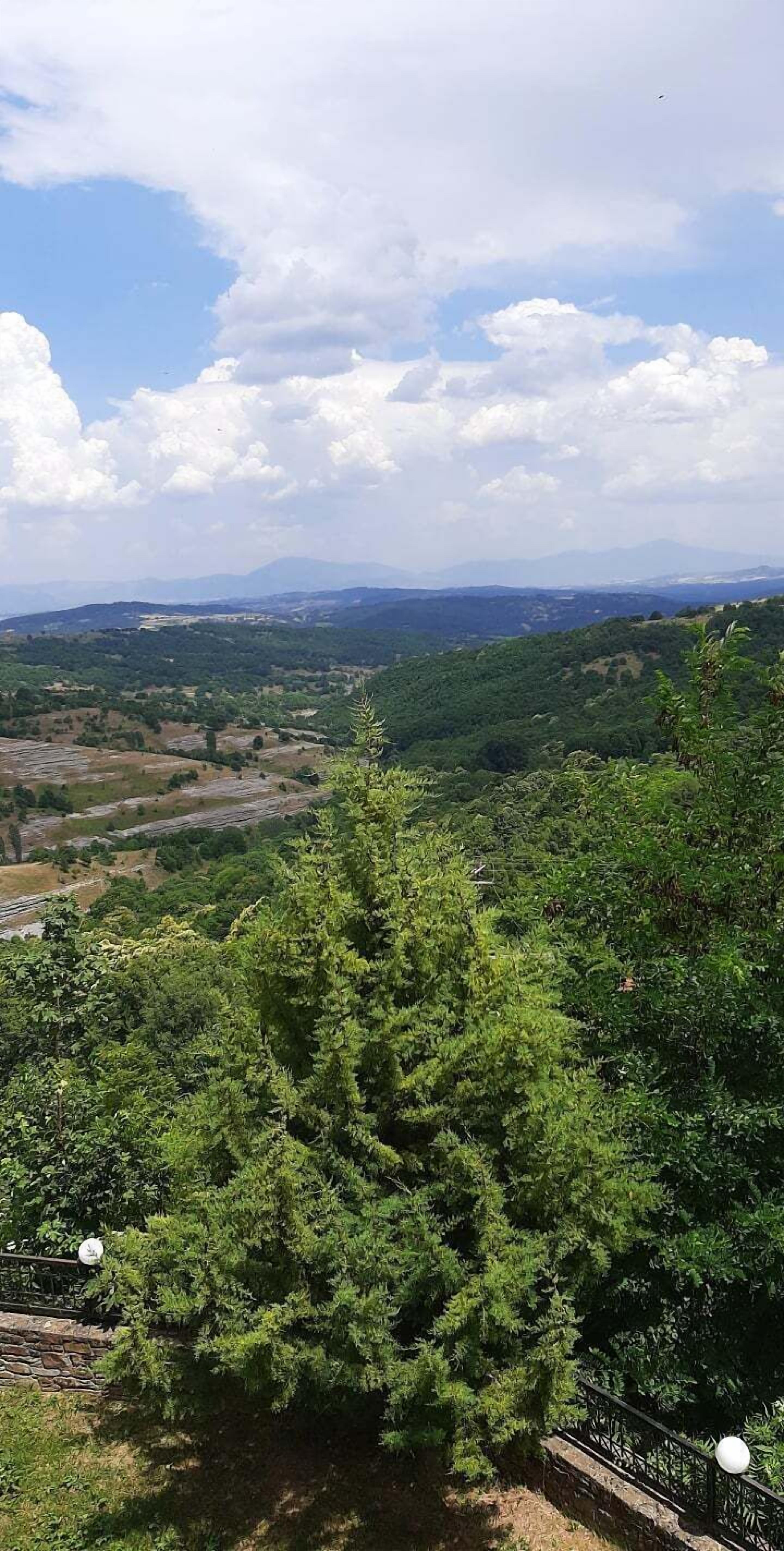A mountainous landscape with dense green foliage and a clear sky.