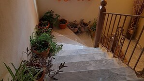 A marble staircase with potted plants on either side, leading to a landing with a wooden railing. - Guest House Ilektra (Voio)