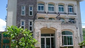 A multi-story building with a stone facade, multiple balconies, and large windows. - MaMaLuLu Hostel (Hengchun)