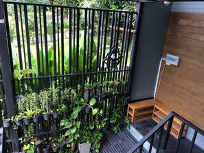 A balcony with a black metal railing, wooden steps, and a small wooden bench. - Decho Hostel (Koh Lipe)