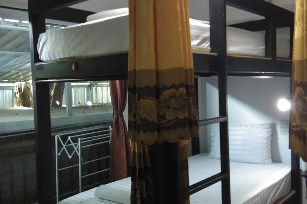 Dormitorio con literas, cortina, barandales metálicos y ventana con cortinas.