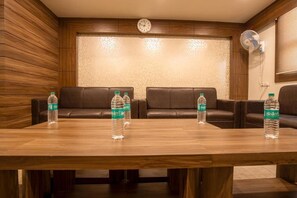 Una sala de conferencias con una mesa de madera, cuatro sofás de cuero y un reloj en la pared.