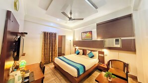 Una habitación de hotel con una cama, mesita de noche, lámpara y ventilador de techo.