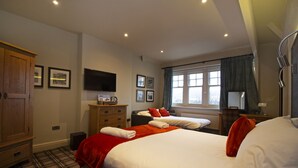 Een hotelkamer met een groot bed, een kledingkast, een bureau met lamp en een televisie aan de muur.