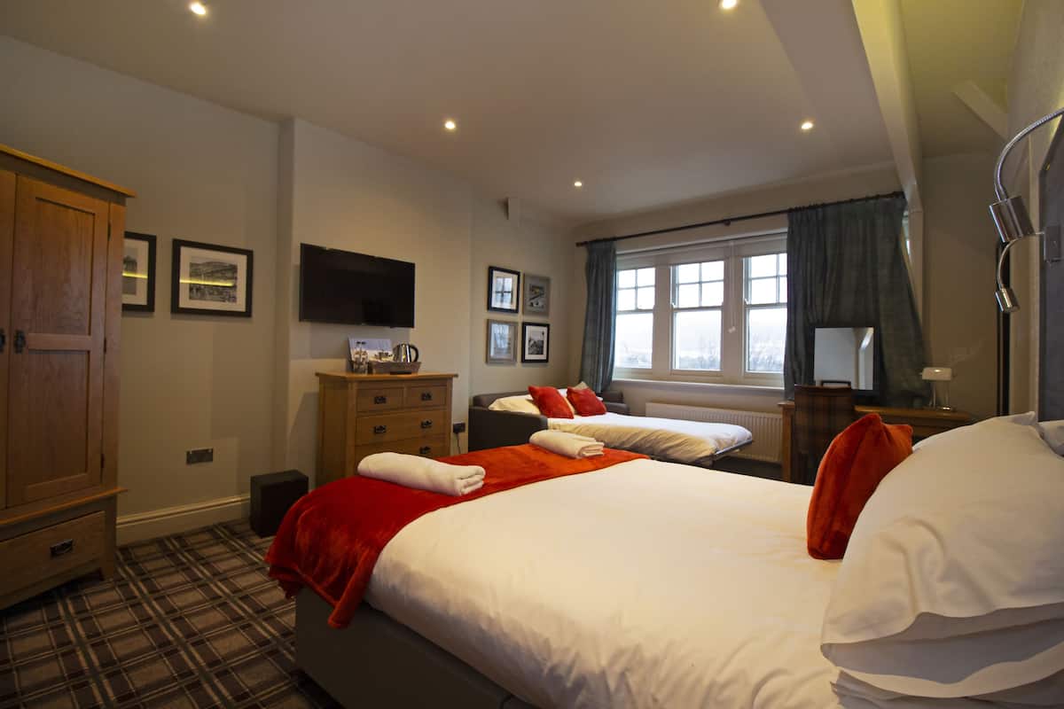 Een hotelkamer met een groot bed, een kledingkast, een bureau met lamp en een televisie aan de muur.