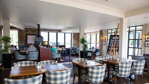 Een restaurant met een stenen muur, grote ramen en geruit stoelen.
