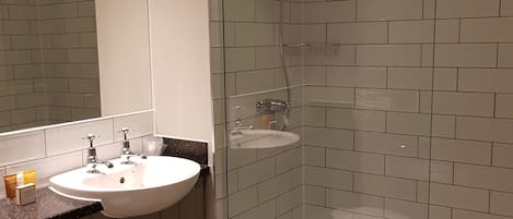 Een moderne badkamer met een wit wastafelmeubel, een douche met glazen wanden en een betegelde muur.