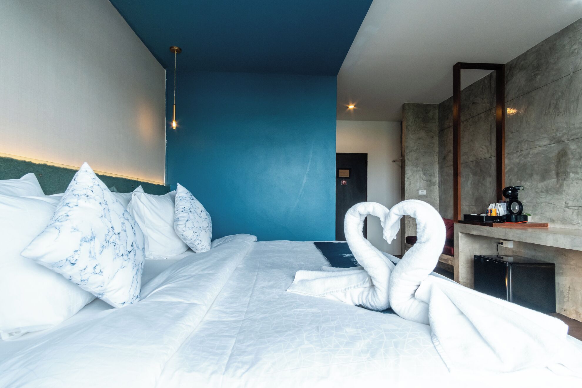 Ein Hotelzimmer mit einem großen Bett, blauer Akzentwand, Kamin und Spiegel.