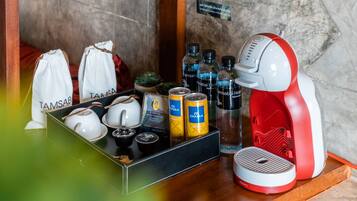 A tray with tea sets, cans of beverages, and a red and white coffee machine on a wooden surface.