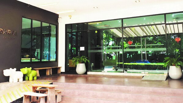 Un hall d’entrée moderne avec un banc, des plantes en pot et une entrée en verre.