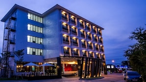 A multi-story hotel with a modern design, featuring a prominent entrance with a covered outdoor seating area.