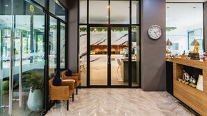 A modern reception area with a marble floor, wicker chairs, a wooden reception desk, and a clock on the wall.