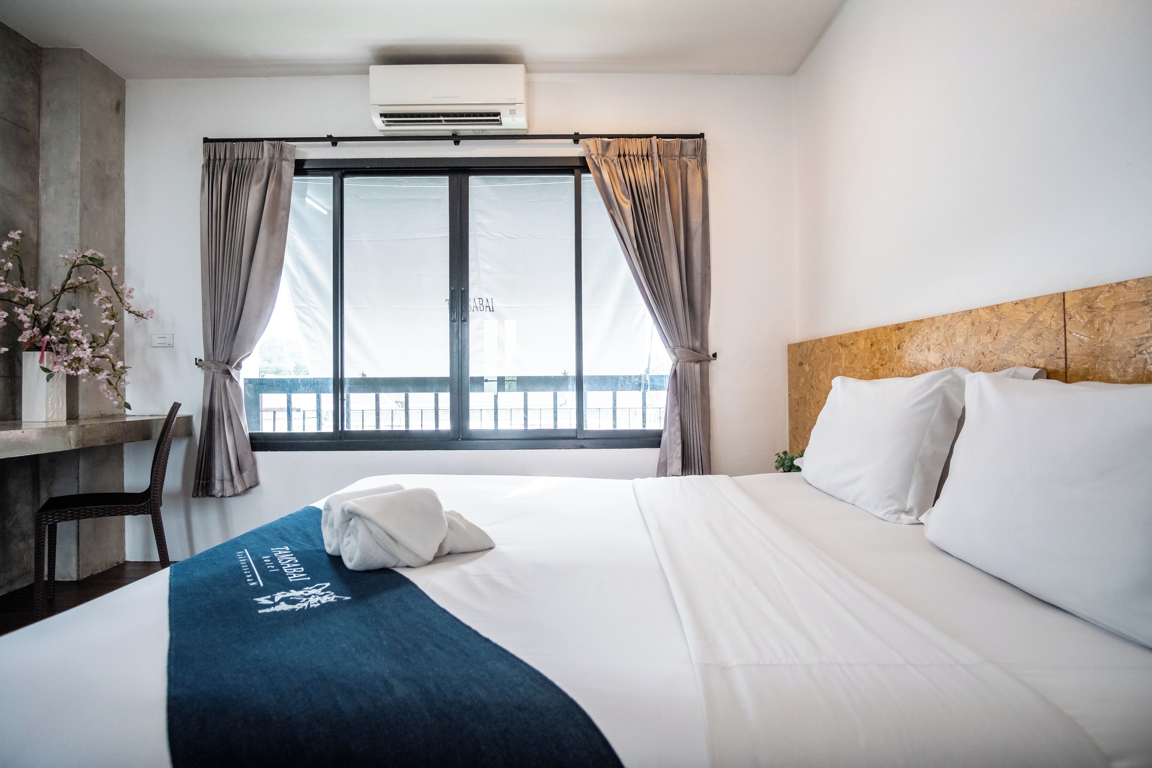 Una camera d'albergo con un letto, una scrivania e una finestra con tende.