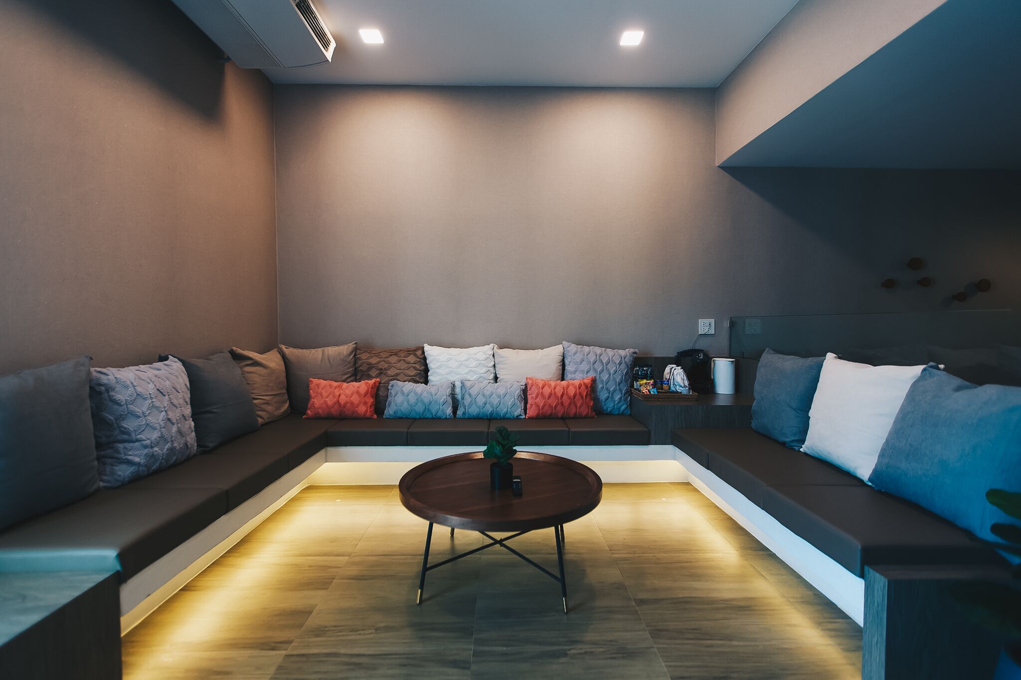 Una sala moderna con un sofá modular, una mesa de centro redonda e iluminación empotrada.