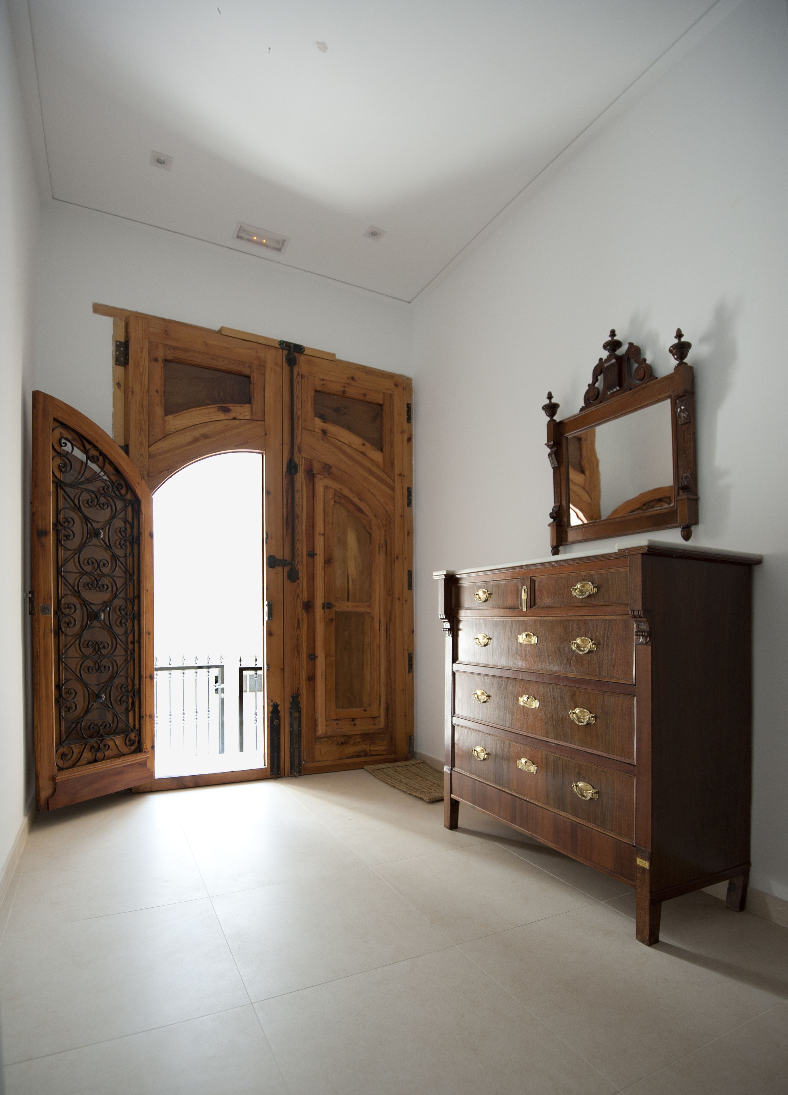 A room with a wooden door, a dresser with multiple drawers, and a mirror on top.