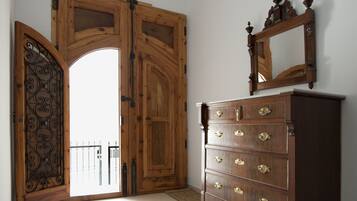 A room with a wooden door, a dresser with multiple drawers, and a mirror on top.