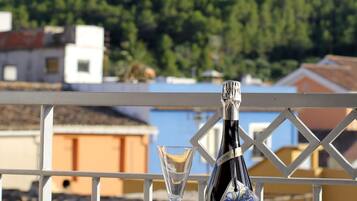 A table with a bottle of wine, a wine glass, and a decorative bottle label. The table is outdoors with a mountain and forest in the background.