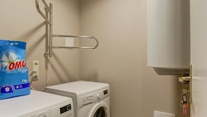A laundry area with a washing machine, dryer, and a bag of detergent. - Liberty Airy (Riga)