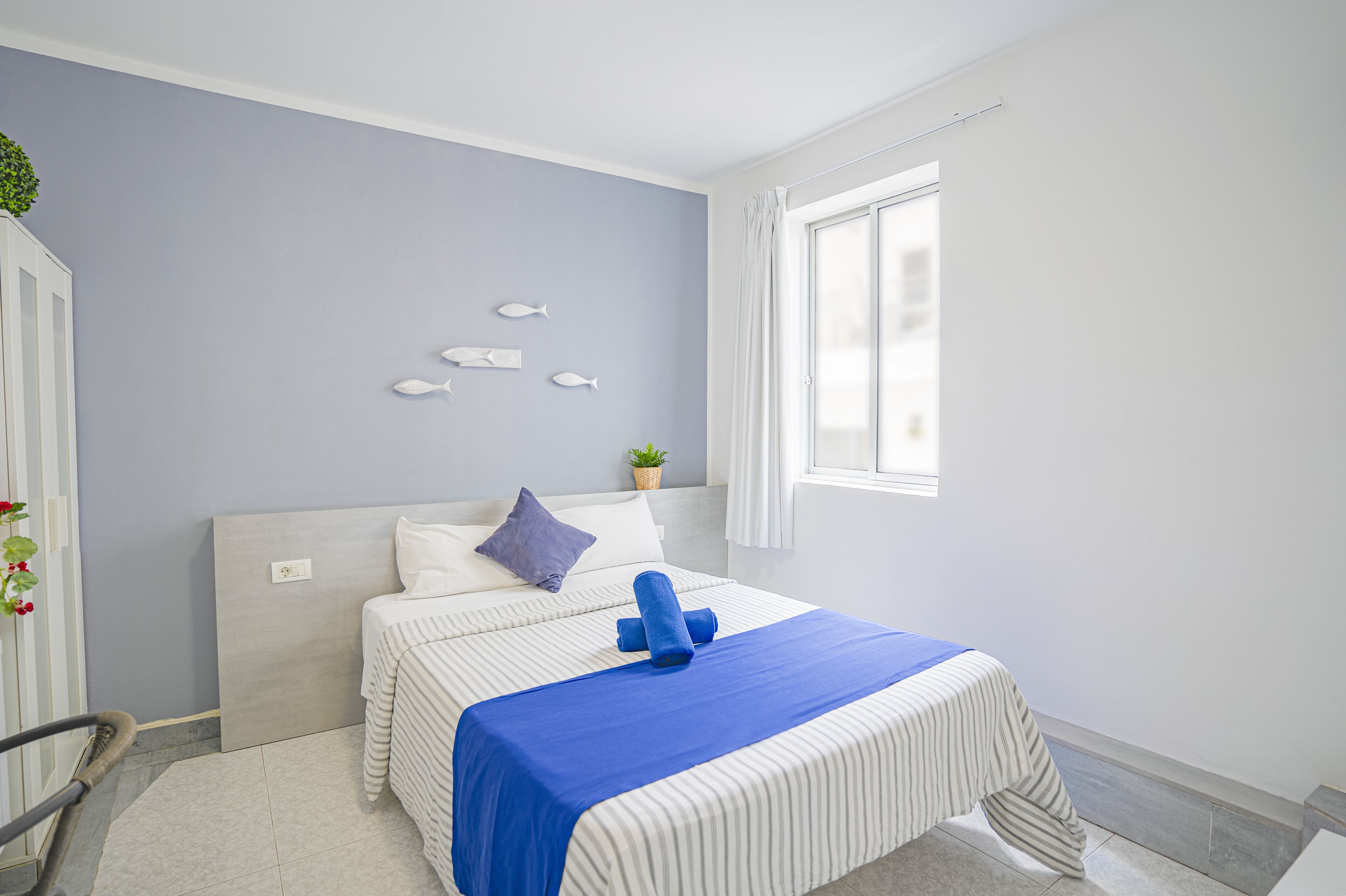 A neatly arranged bedroom with a bed, pillows, and a blue blanket.