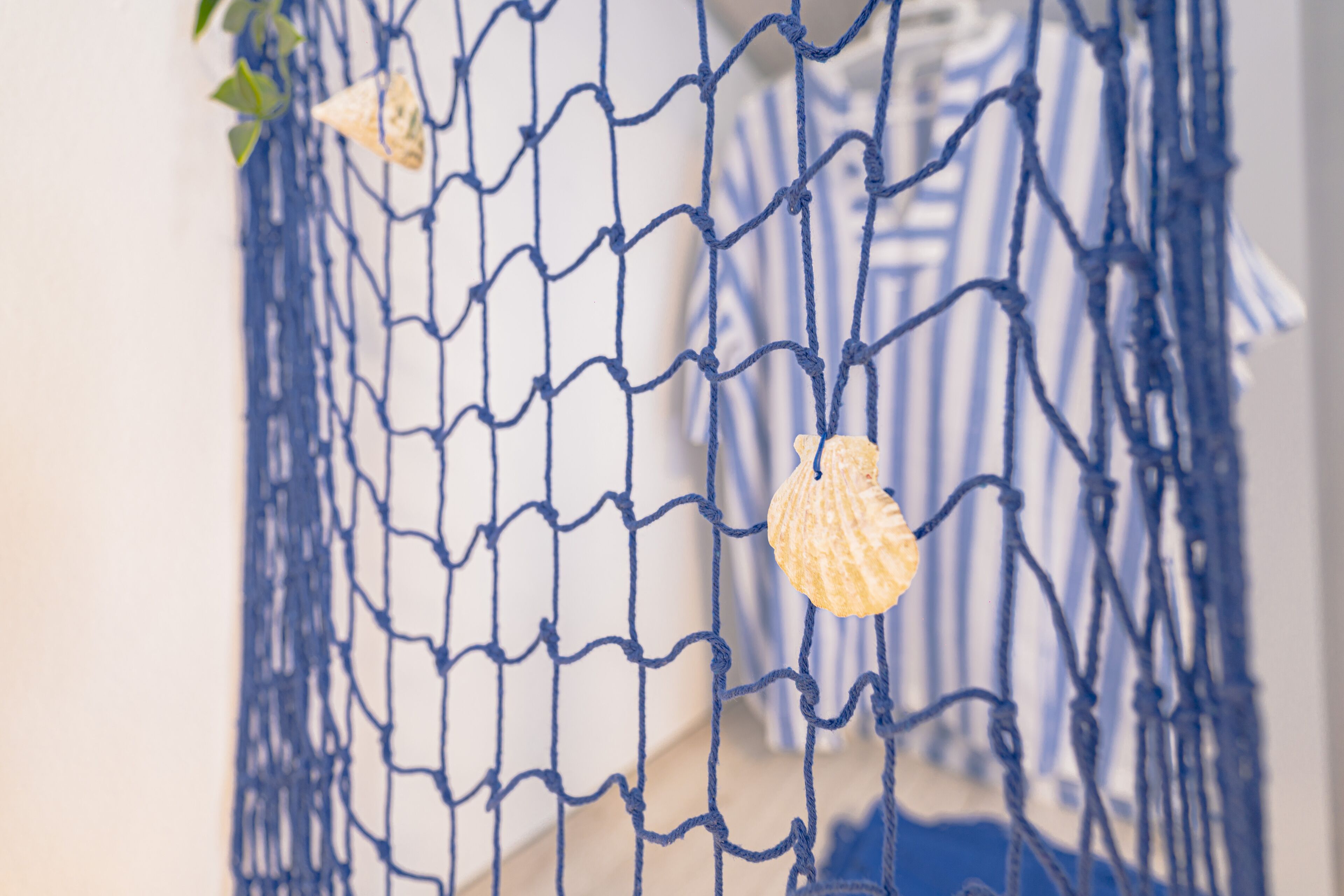 A close-up of a blue net with seashell decorations.