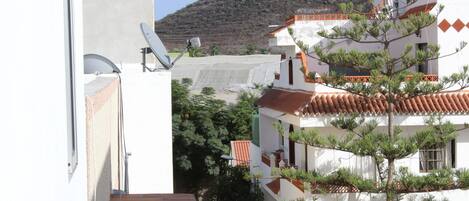 Ein mehrstöckiges Gebäude mit weißen Wänden und roten Ziegeln, umgeben von Grünflächen und einem Berg im Hintergrund.