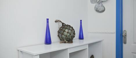 Een witte console tafel met twee blauwe vazen, een decoratieve bol en een wandventilator.