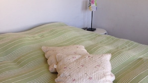 A bed with a green striped bedspread and two decorative pillows.
