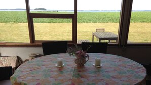 A round table with a floral tablecloth, two candles, and a vase with flowers.