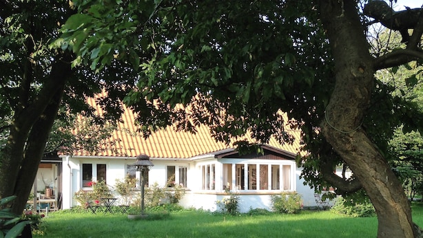 A house with a tiled roof, surrounded by a well-maintained lawn and trees.