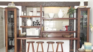 A kitchen with wooden shelves, stools, and various kitchenware.