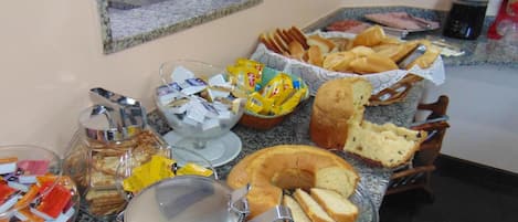 A breakfast buffet with various food items and a coffee pot on a granite countertop.