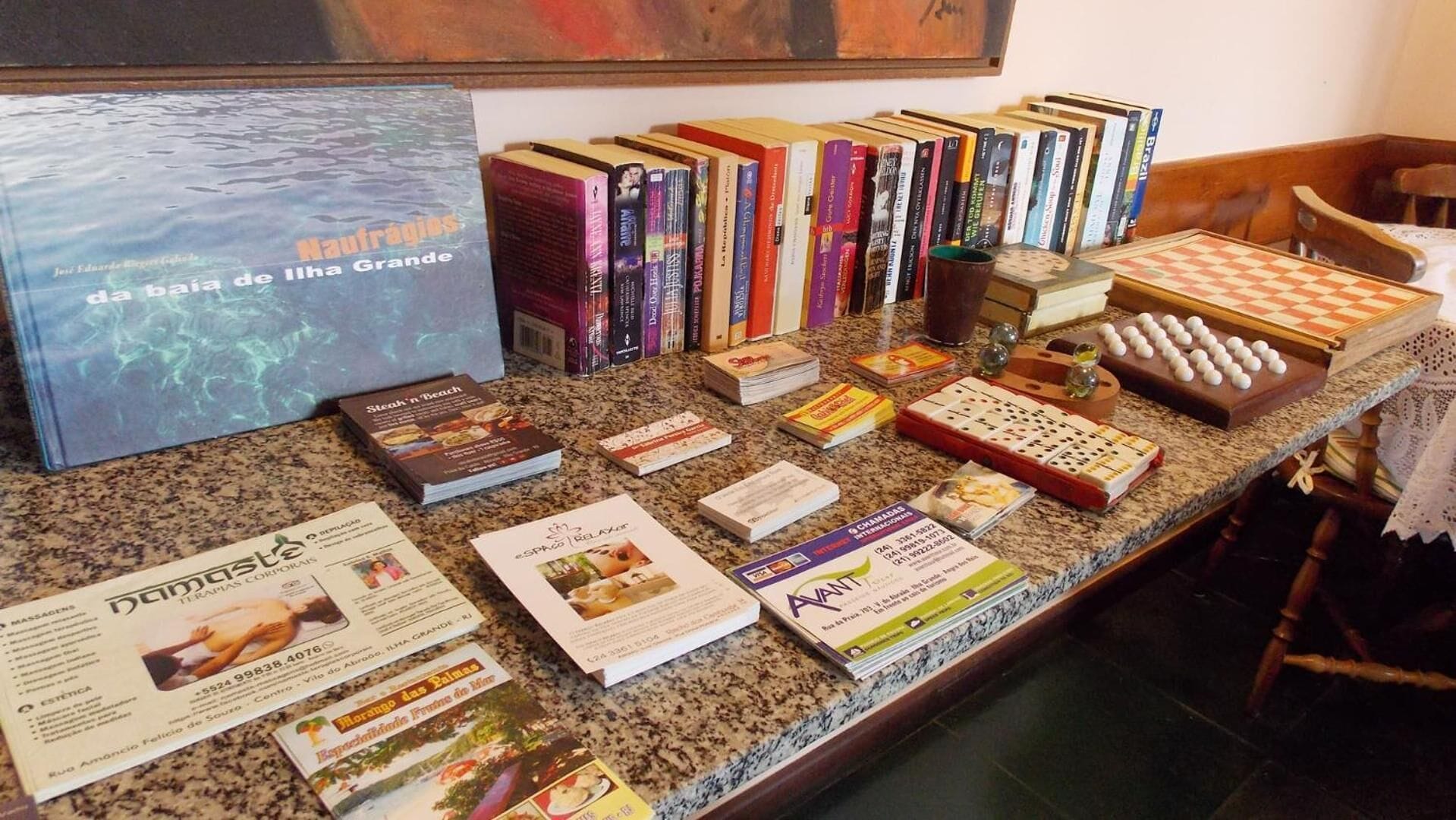 Un mostrador con una variedad de libros, folletos y un tablero de ajedrez.