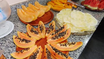 Obstteller mit Papaya-, Mango- und Ananasscheiben auf einer Granit-Arbeitsplatte.