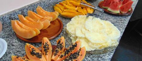 A buffet table with various fruits including papaya, mango, pineapple, and watermelon.