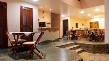 A restaurant with a tiled floor, wooden chairs, a counter with a tiled backsplash, and a painting on the wall.