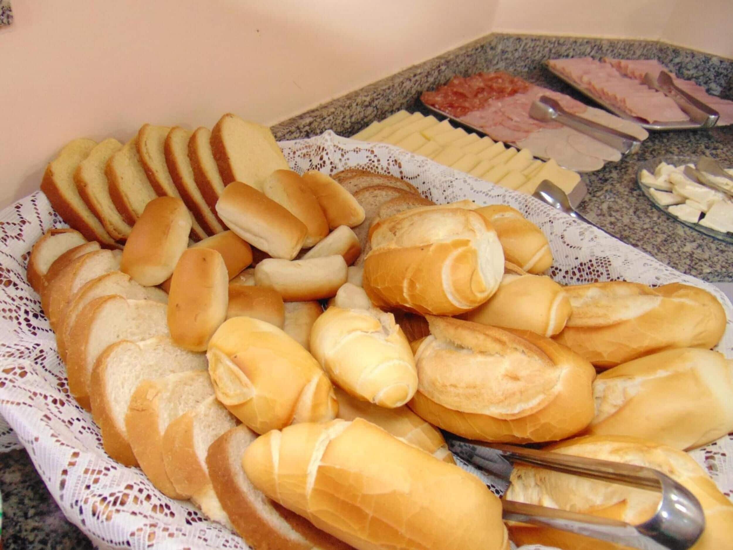 Una bandeja con varios tipos de pan, incluyendo baguettes y bollos, sobre una mesa.