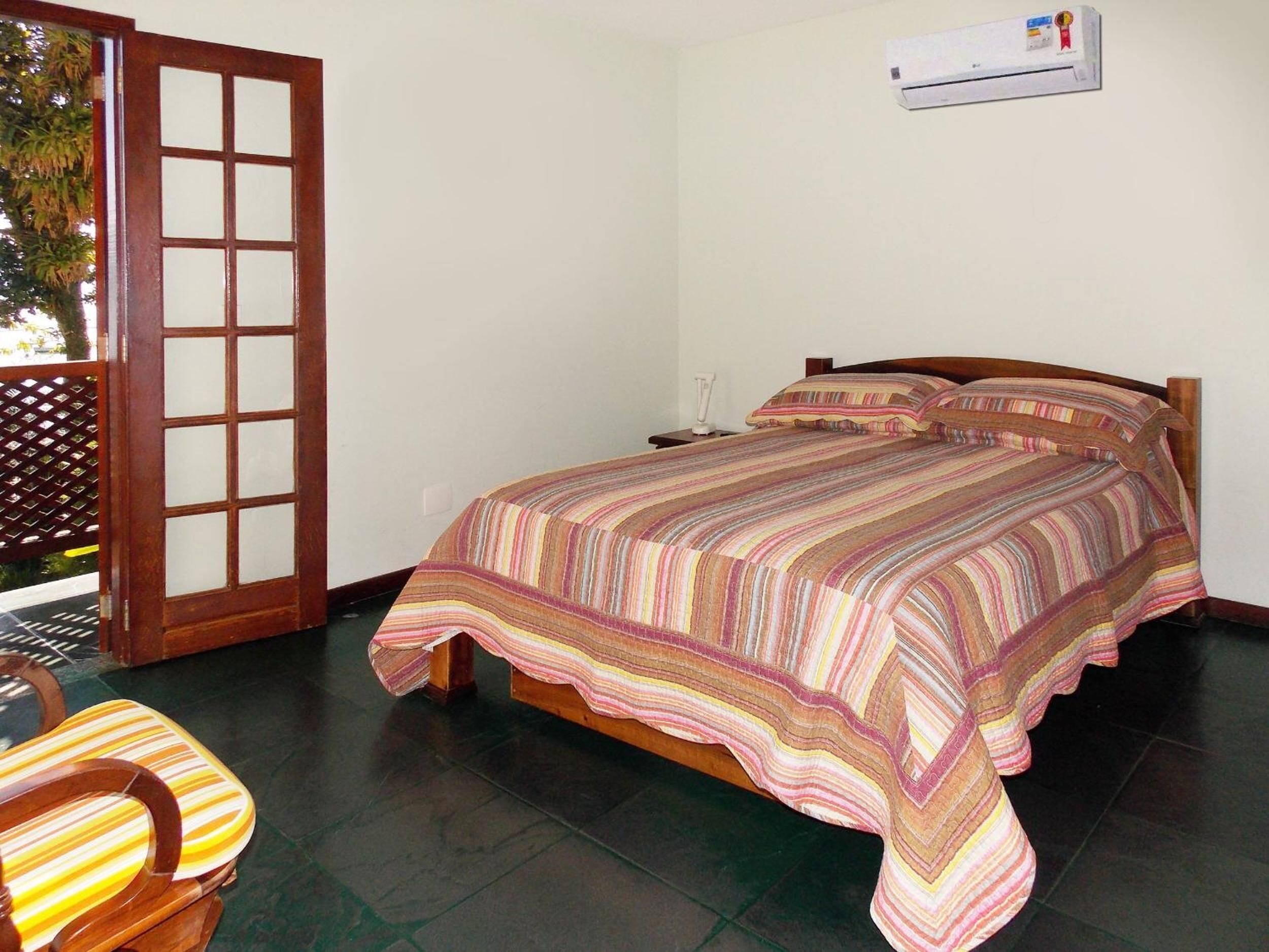 A bedroom with a bed, a nightstand, a chair, and a sliding door.