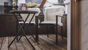 A wooden deck with two white furry chairs and a small round table. - Margarethenstein Boutique Hotel & Apartment (Kaprun)