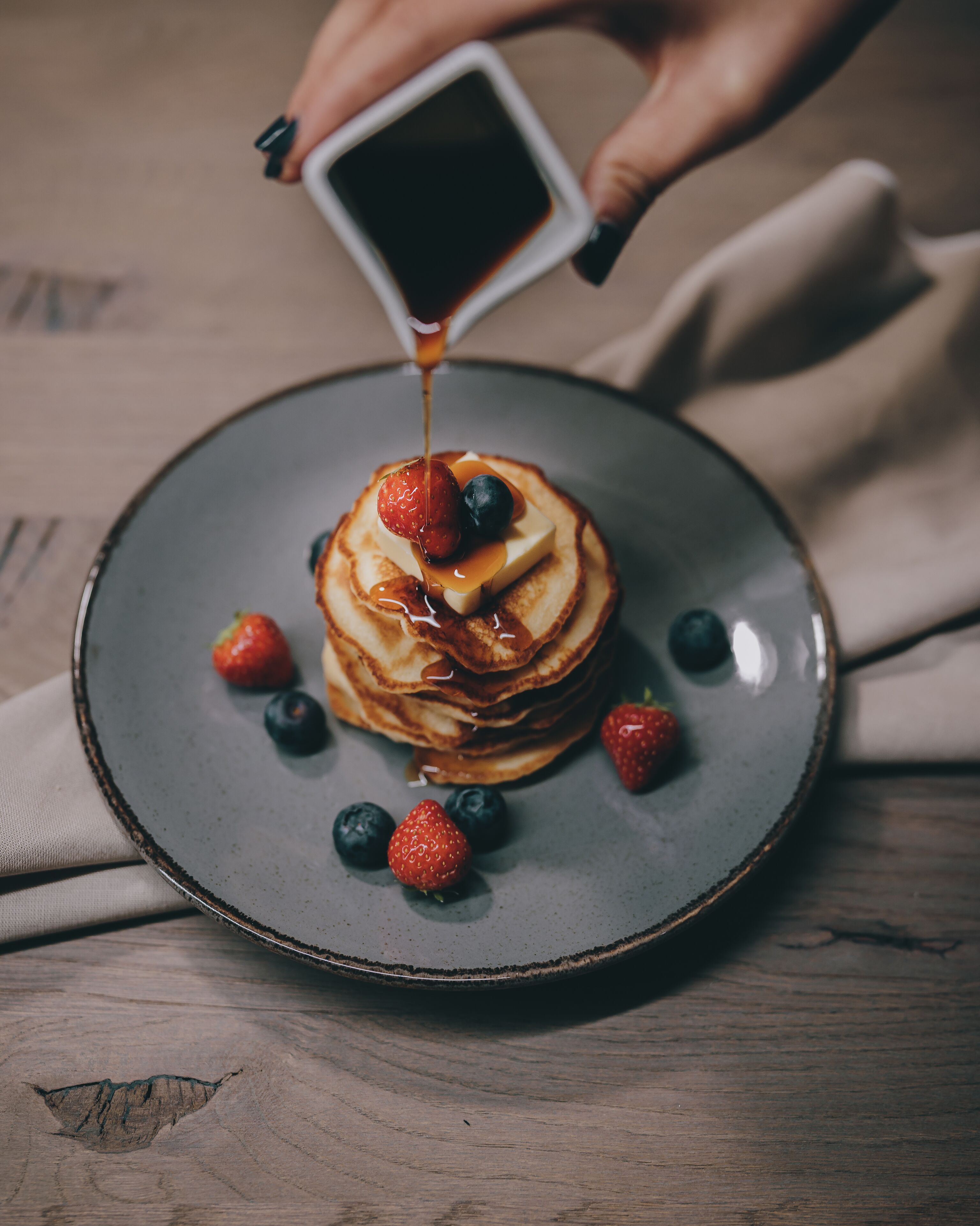A stack of pancakes with syrup and berries on a plate.