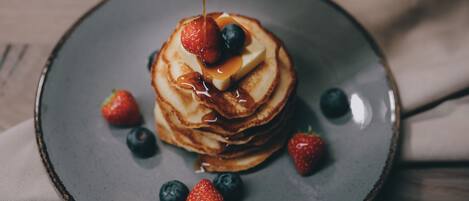 A stack of pancakes with syrup and berries on a plate.