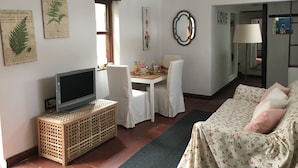 A living room with a television, a dining table with chairs, a sofa, and a lamp. - La Casita de Las Palmas VV (Las Palmas de Gran Canaria)