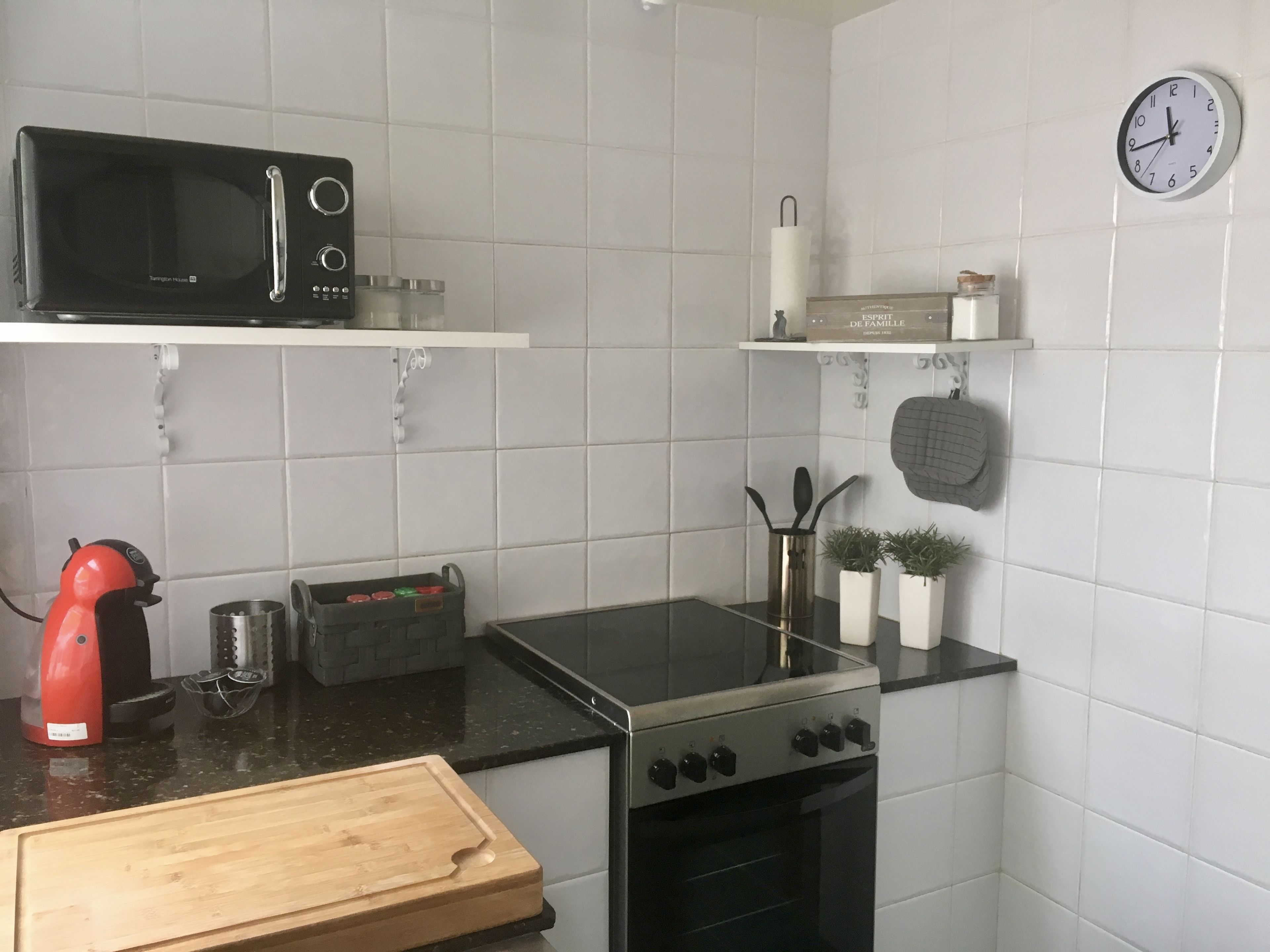 Una cocina moderna con microondas, estufa y horno. Hay dos pequeñas macetas con plantas sobre la encimera.