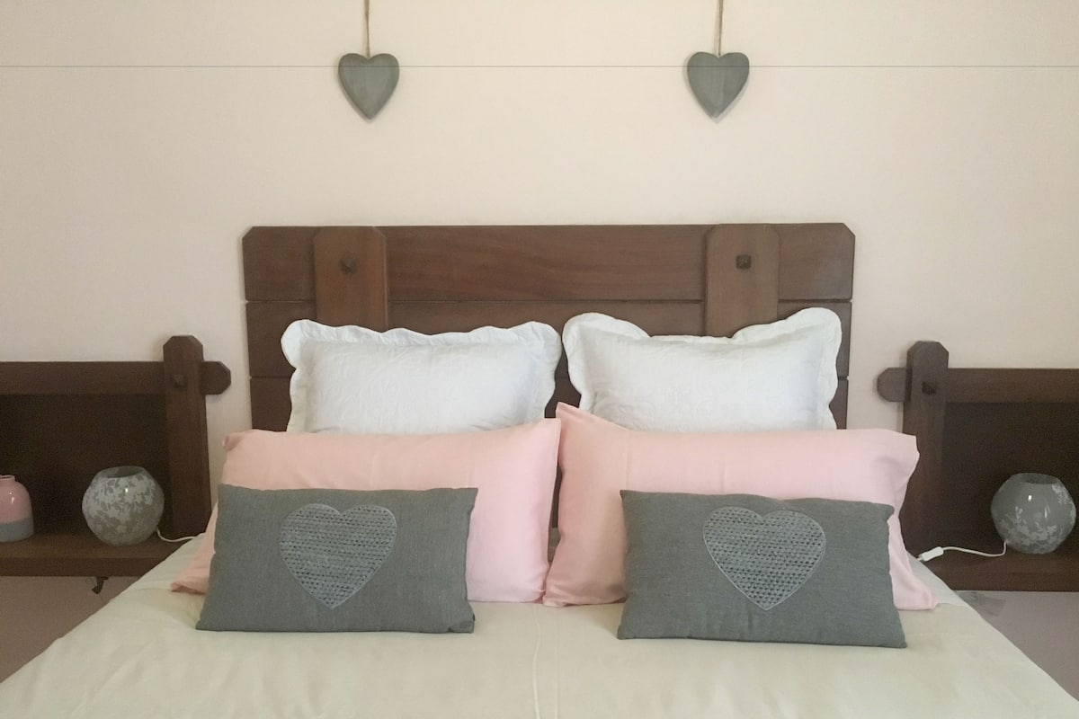 A bed with two pillows, a wooden headboard, and heart-shaped wall decorations.