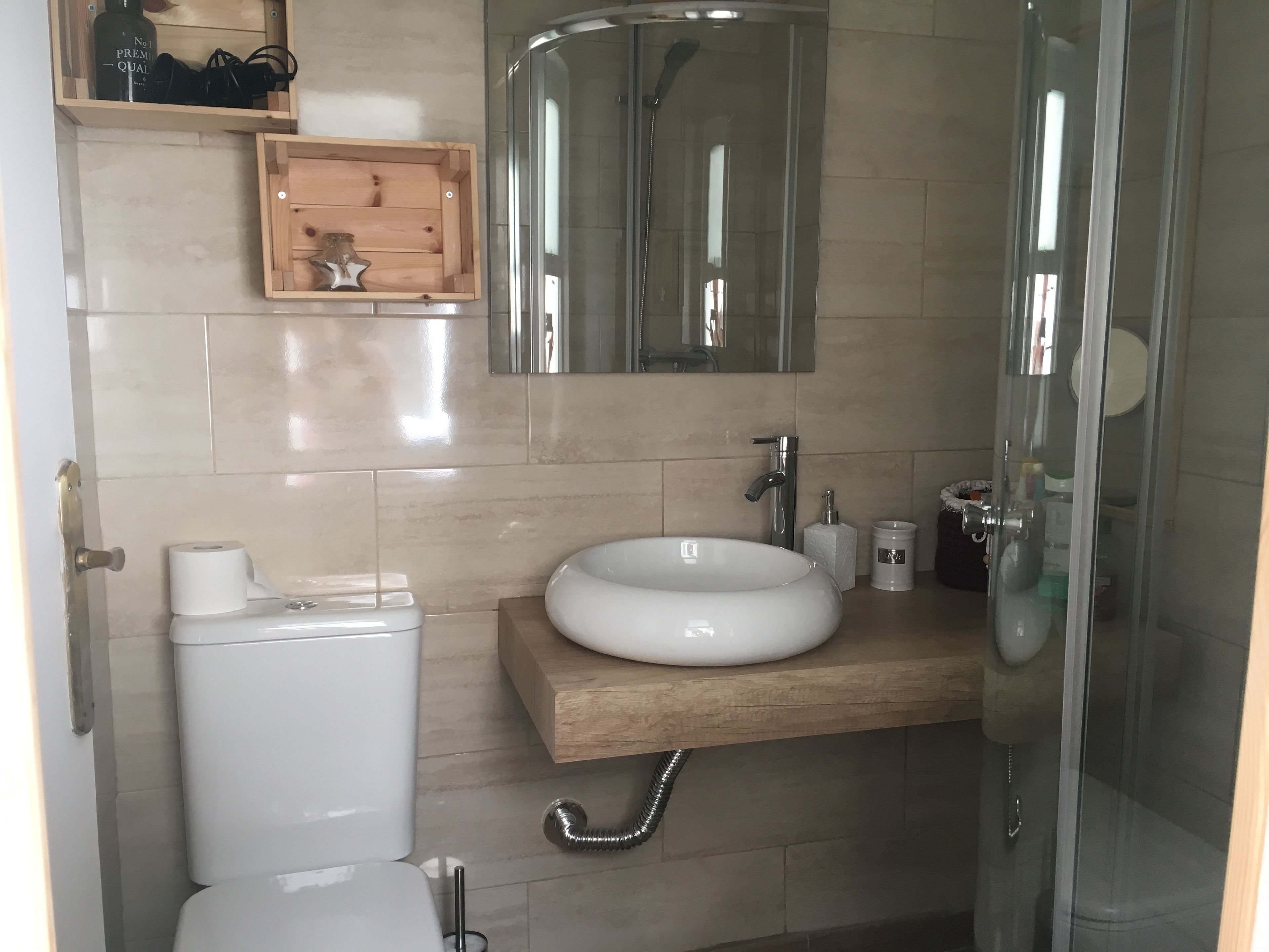 Un baño moderno con inodoro, lavabo, espejo y ducha.