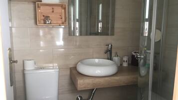 Un baño moderno con inodoro, lavabo, espejo y ducha.