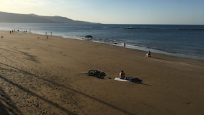 A wide sandy beach with footprints, a few people, and a calm sea. - La Casita de Las Palmas VV (Las Palmas de Gran Canaria)