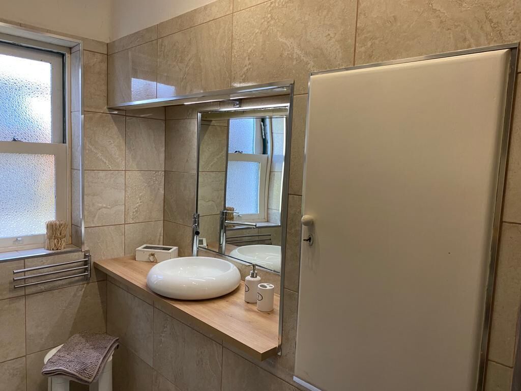 A bathroom with a large mirror, a sink, a towel rack, and a toilet.